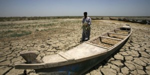 An Iraqi man walks past a canoe siting on dry, cracked earth in the Chibayish marshes near the southern Iraqi city of Nasiriyah on June 25, 2015. Marsh areas in southern Iraq have been affected since the Islamic State group started closing the gates of a dam on the Euphrates River in the central city of Ramadi, which is under the jihadist group's control. AFP PHOTO / HAIDAR HAMDANI